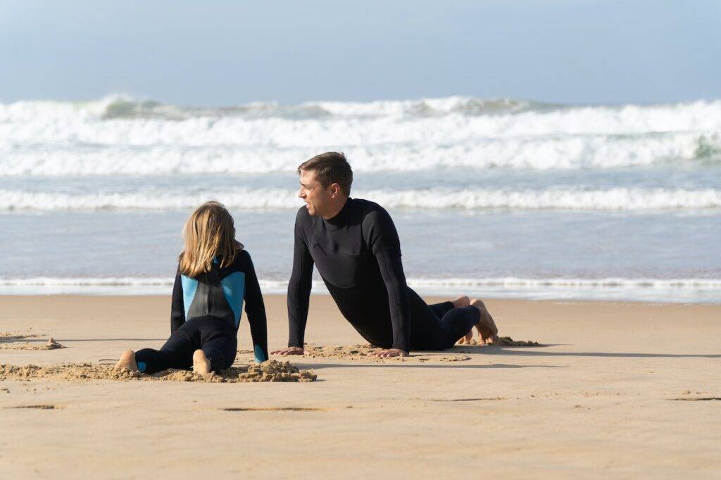A man and a child exercising at the beach - Hobbies For Dads